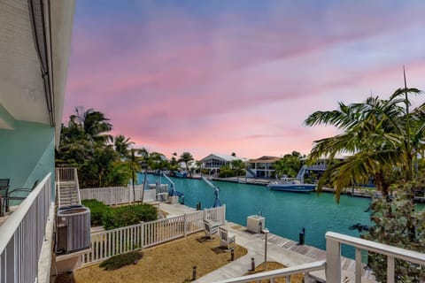 Tranquil waterfront living at its finest—sunset skies, swaying palms, and boats docked along a peaceful canal.