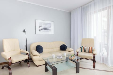 A cozy living area featuring a comfortable sofa set, coffee table, and wall art, bathed in natural light from a large window. Perfect for relaxing or spending time with loved ones.