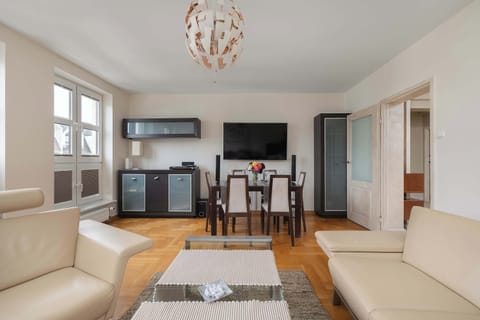 A well-lit living and dining area featuring a comfortable sofa, TV setup, and a dining table for gatherings. Modern design elements enhance the aesthetic appeal.