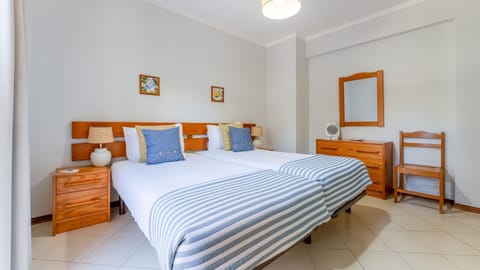 Fresh linens, nautical stripes, and a calm ambiance for restful nights. #HolidayHome #TwinBedroom #LovelyStayPortugal #CoastalRetreat