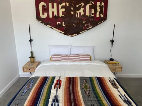 Bedroom 1 queen bed from foot — striped Southwest coverlet and bedside table with lamp