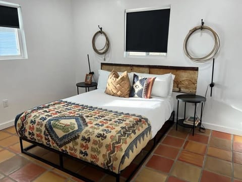 Tuff`s Place main bedroom — king bed with colorful Southwest patchwork quilt, rope wall art, terra cotta tile