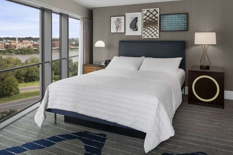 Corner king room with river views and soft gray and navy decor
