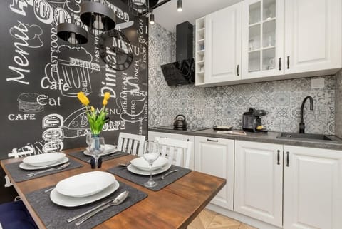 A stylish kitchenette with modern cabinetry, patterned backsplash, and sleek appliances, perfect for compact yet functional cooking.