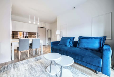 A bright and airy living space invites relaxation with its plush blue sofa and stylish marble coffee table.  Large windows flood the room with natural light, creating a cheerful and welcoming atmosphere.