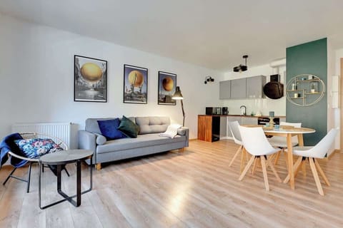 A spacious living room with a gray sofa, a coffee table, and a dining area with modern chairs, enhanced by large windows for natural light.