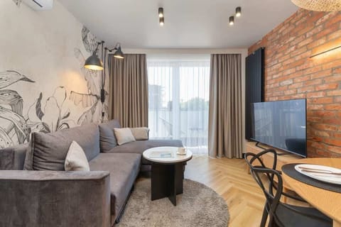 A stylish living room with exposed brick walls, a grey sofa, and a round coffee table.

