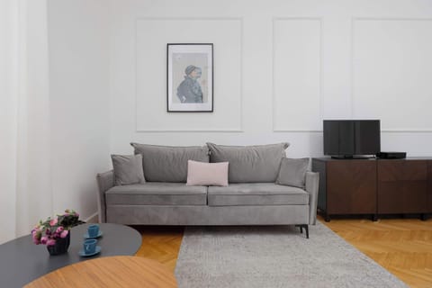 A bright, modern living space featuring a gray sofa, a coffee table, and a soft rug, with simple wall art and decorative touches.
