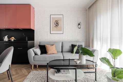 Refined minimalism, blending warm coral tones, textured white brick, and sleek black accents with cozy furnishings, soft light, and vibrant greenery for a sophisticated yet inviting ambiance.