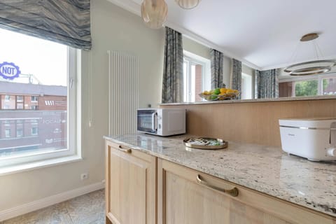Modern kitchenette with sleek wooden fronts, black worktop and fully fitted appliances.