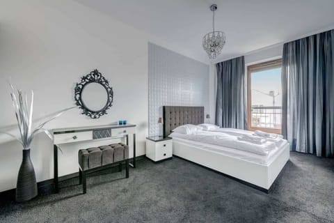An elegant and peaceful bedroom that exudes luxury and comfort. The large bed with a comfortable upholstered headboard and subtle touches such as stylish night lamps and an elegant mirror create the perfect space for relaxation.