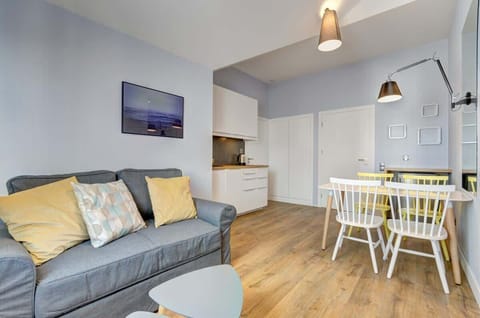 A modern living room offer a gray two-seater sofa with decorative cushions in shades of yellow for relaxation. 