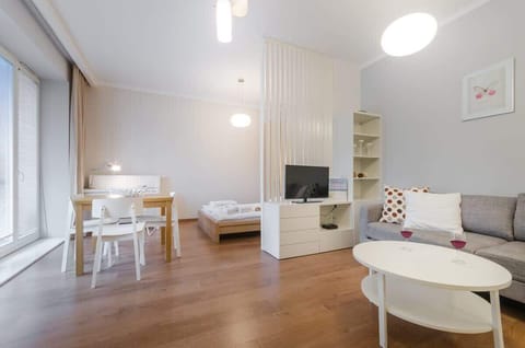 The living room combines modernity with comfort, large sofa, stylish coffee table, and minimalist shelves create an elegant space for relaxation. Neutral wall colors enhance the room's brightness, and large windows bring in plenty of natural light.