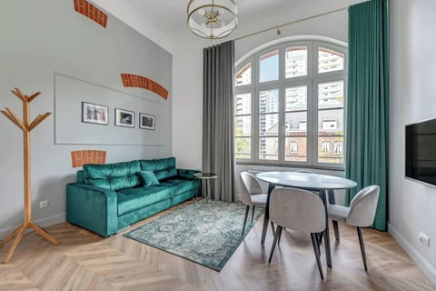 A cozy space featuring a teal sofa, framed artwork, and large windows letting in natural light.