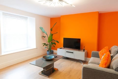 Stylish lounge with sofa bed, TV and orange feature wall