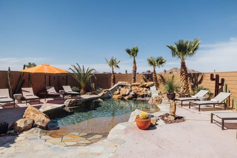 Heated pool with natural rock waterfall and lounge chairs for relaxing.