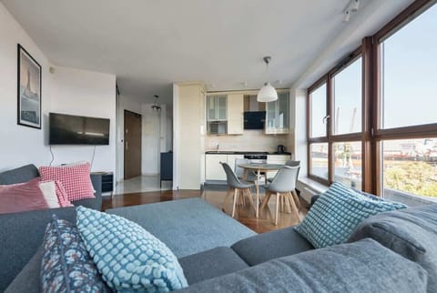 A seamless blend of kitchen, dining, and living areas, with large windows creating a bright and open atmosphere.