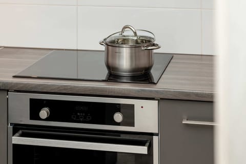 A close-up of the kitchen’s black stove, with a stainless steel pot placed on top.
