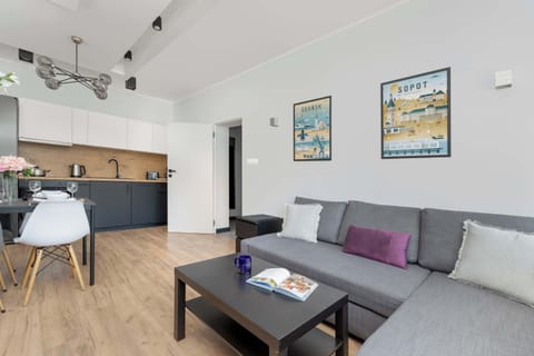A modern living room with a gray sofa, stylish wall art, and a cozy atmosphere. Large windows let in plenty of natural light.