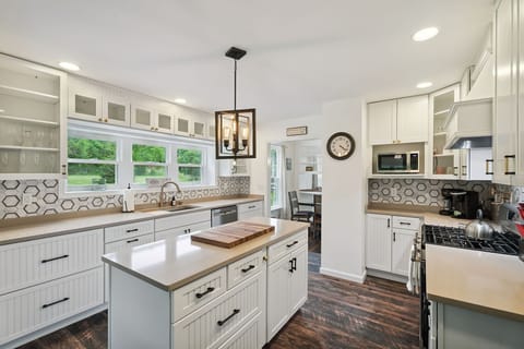 This bright, beautifully updated kitchen features plenty of counter space, open shelving, and scenic views to inspire every meal.