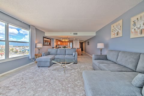 Relax in your spacious living room featuring plush sectional seating and stunning city views through floor-to-ceiling windows.