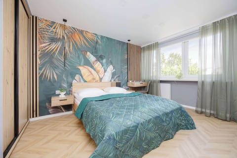 Stylish bedroom with a double bed, floral wallpaper, and large window with sheer curtains.