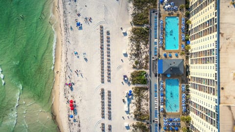 Picture your first glimpse from the air: your resort tower rising right off the sand, two glittering pools waiting below, and the Gulf stretching out as far as you can see, sun already dancing on the water.