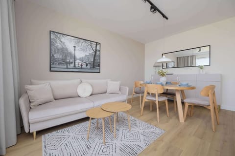 A modern living room with a light sofa, wooden coffee table, and stylish black-and-white wall art.