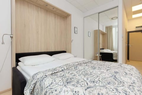 A cozy bedroom with a double bed, wooden headboard, and soft bedding in neutral tones.

