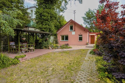 Exterior view of a charming house with a paved garden path and trees.