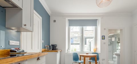 Kitchen with wood counters and round dining table by large bright window.