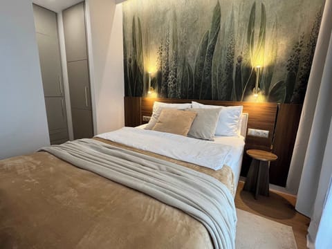 A cozy bedroom with a double bed and a glowing feature wall behind the headboard. Warm lighting and neutral tones create a relaxing atmosphere.