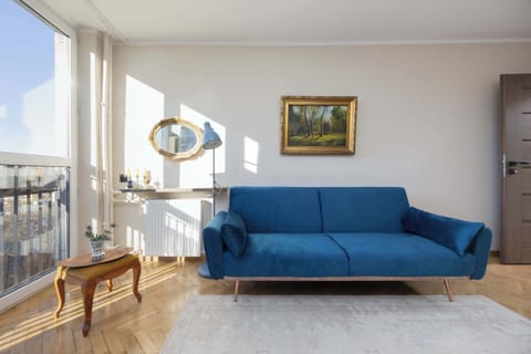 A bright living room featuring a blue sofa, a coffee table, and large windows allowing in ample natural light.