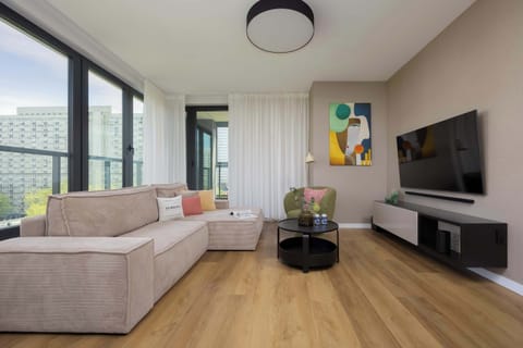 Modern living room with a corner sofa, Smart TV and access to balcony.