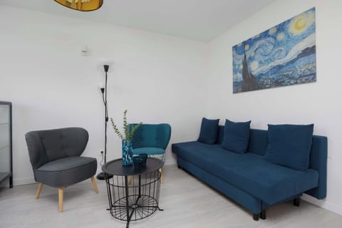 A cozy living room with a teal sofa, abstract wall art, and a modern coffee table, decorated with a standing lamp in the corner.