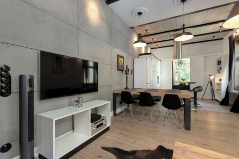A cozy living and dining space with modern decor and TV setup. Black accents create a sleek look.
