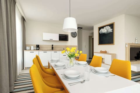 A modern dining room with a large table, elegant chairs and stylish lighting. The space is bright and airy, ideal for shared meals and gatherings.