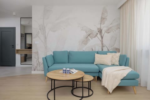 A bright living room with a teal sofa, marble-accented wall, and minimalist decor exudes modern elegance.