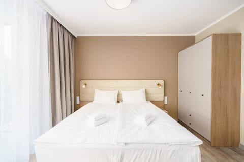 A spacious bedroom with a large bed, soft linens, and built-in wardrobes, featuring a neutral color palette.
