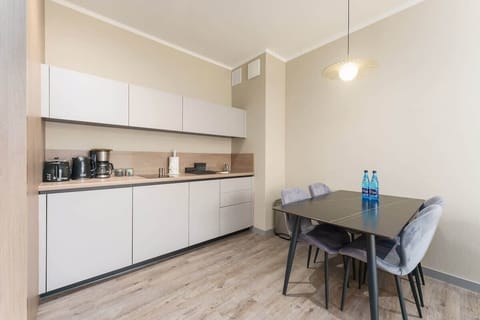 A sleek and compact kitchen with white cabinets, wooden finishes, and a small dining table.