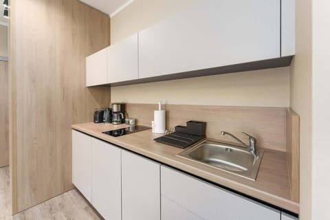 A minimalist kitchen design with white cabinetry, a wooden backsplash, and a clean layout.
