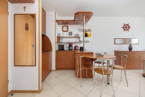 Kitchenette with induction hob, microwave, refrigerator with freezer, electric kettle, coffee maker and dining area.