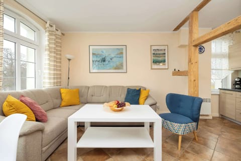 A cozy living room with a blue and yellow color scheme, featuring a comfortable sofa, a white coffee table, and large windows allowing plenty of natural light.