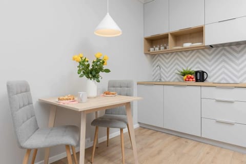 A cozy dining space featuring a small wooden table with chairs, accompanied by a vase with fresh yellow flowers. 