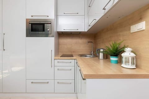 Modern white cabinets, wooden countertop, and small decorative plants.