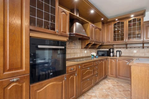 A wooden kitchen with upper and lower cabinets and ample counter space. Fully equipped for meal preparation.