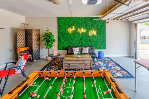Modern entertainment space with a foosball table, greenery wall, and chill lounge setup — great for family or group fun.