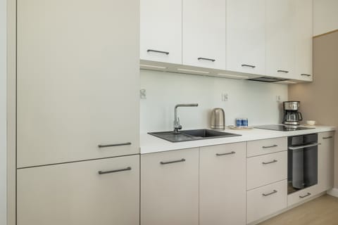 A compact kitchen with modern appliances, white cabinetry, and neutral finishes.