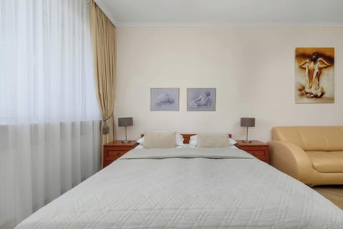 The sleeping area of the studio with white bedding and pictures above the bed highlights the elegant and harmonious character of the interior.
