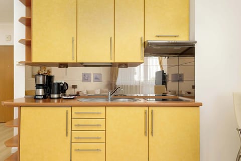 The studio's open kitchen impresses with modern cabinetry, full appliances such as an induction cooktop, overflow coffee maker and a functional dining table, ideal for shared meals.